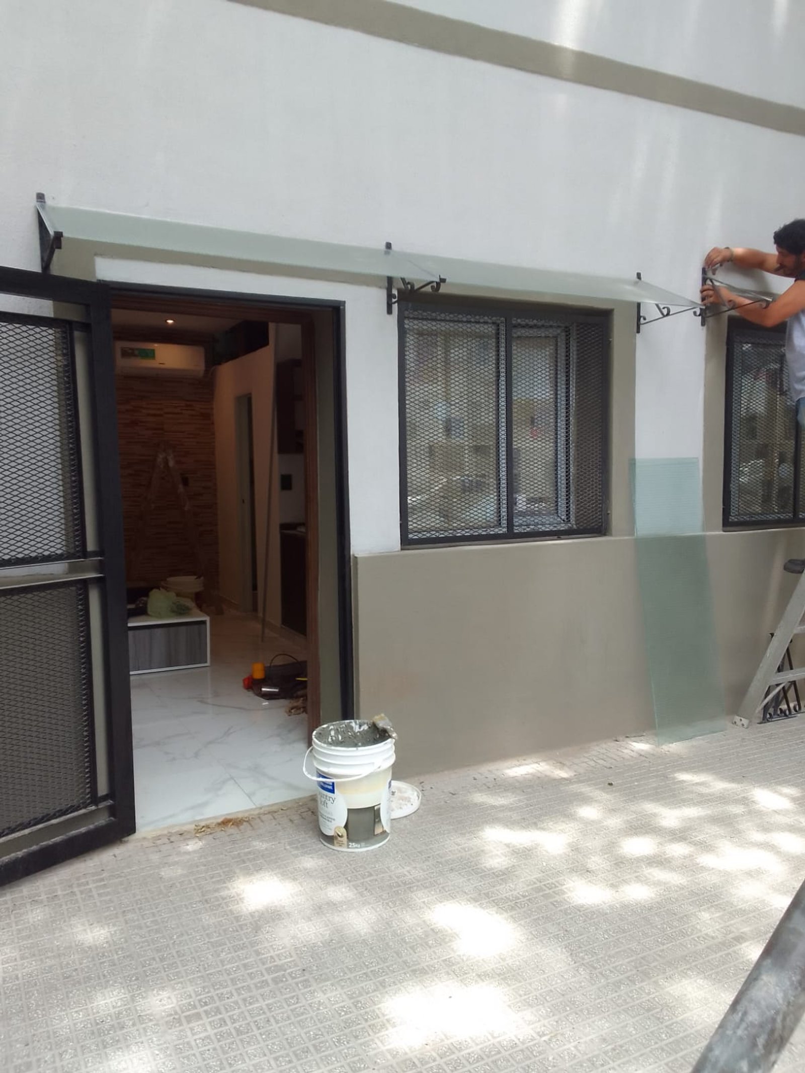 persona instalando toldo sobre ventana, obra exterior — proyecto Departamentos para turistas en Barracas, por Arquitecto Guido Niccoli, en Barracas